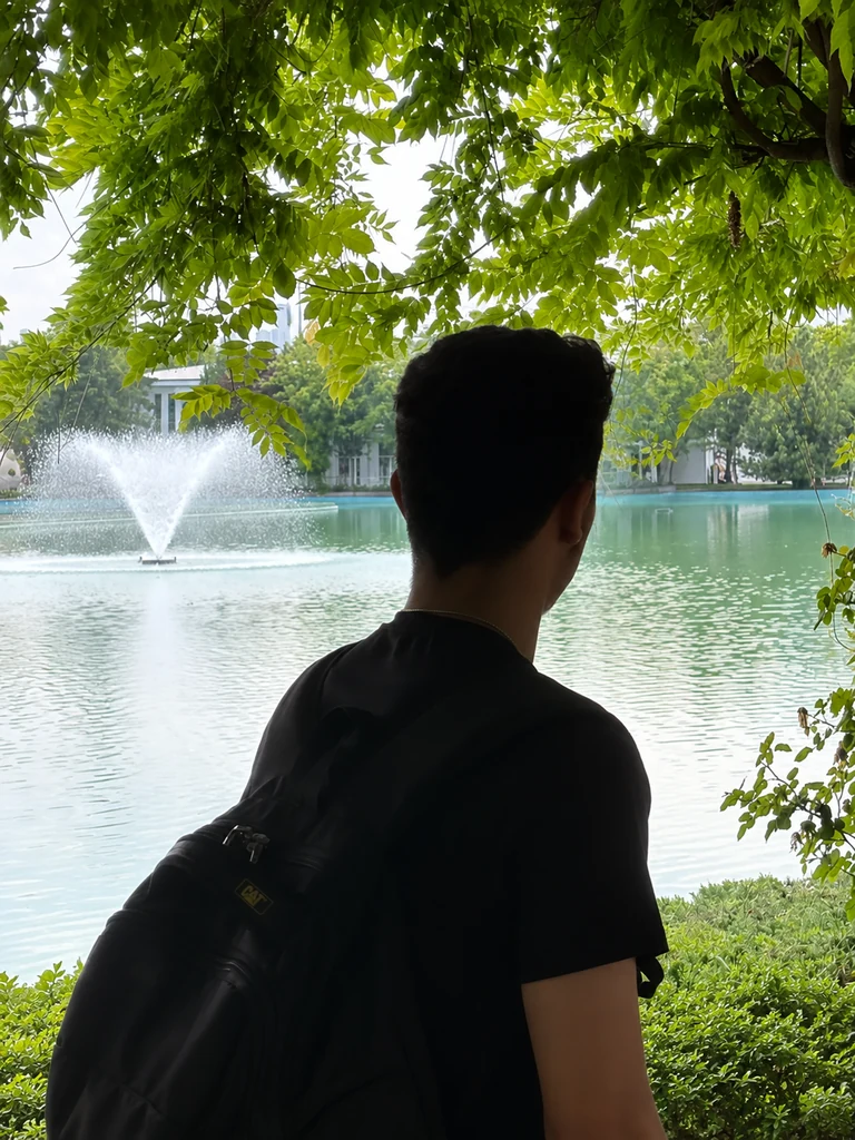 Wahid beside a tree-lined lake